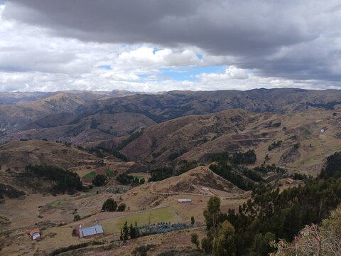 View of mountains and forest with a cloudy sky in the background, Cusco, Peru.
