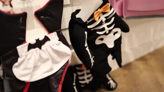 Halloween pet costumes with skeleton bones and vampire outfits hang in a seasonal shop offering spooky clothing for dogs ready for parties photos and playful October mood