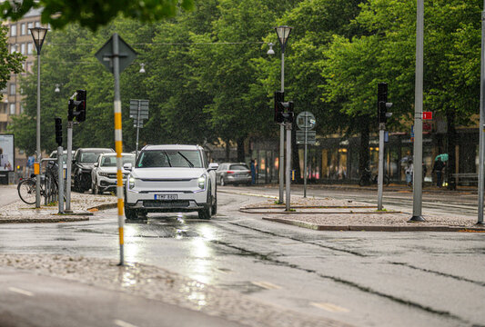 Gothenburg, Sweden - July 28 2026: White Kia EV9 electric SUV driving on rainy street.
