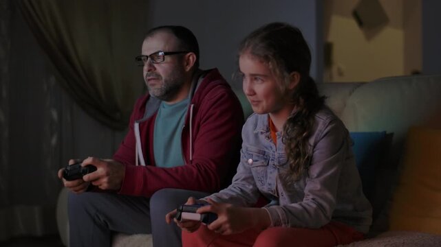 Father and Daughter Expressing Emotions While Enjoying Relaxing Together, Playing Video Games in Front of TV.  Family Time Hobby. Family Having Fun Together at Home in Living Room Playing Video Games.