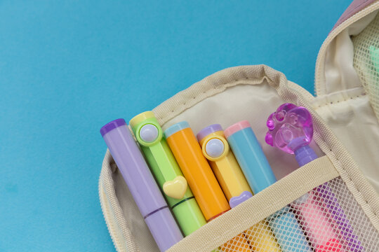 Set of colorful markers in a pencil case with a light blue background on a flat surface