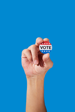 a man holds a vote badge between his fingers