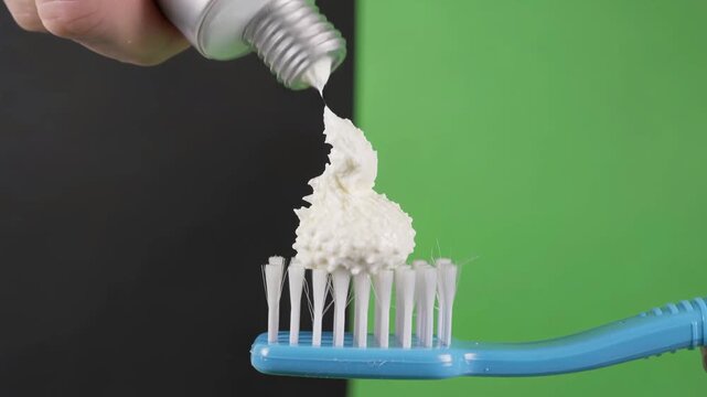 Squeezing white toothpaste onto a blue toothbrush for daily dental hygiene in this motion video clip