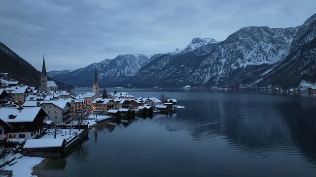 Snow covered alpine lake village at dusk in winter with mountains