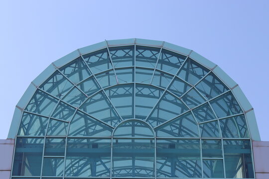 Modern architectural glass dome roof with steel framework against clear blue sky   