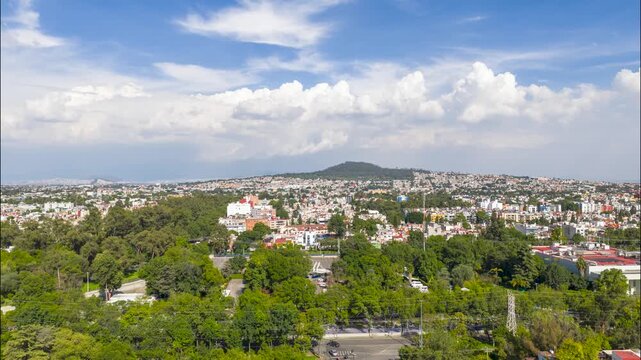 Aerial timelapse of clouds forming over residential neighborhoods and Cerro de la Estrella in Coyoacan, Mexico City, Mexico during a sunny day