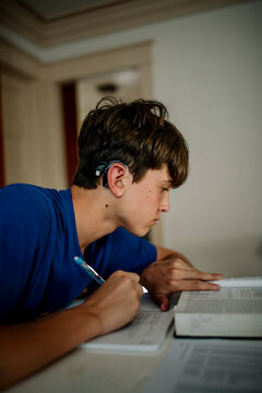 Teen Student with Cochlear Implant Reading and Studying at Home