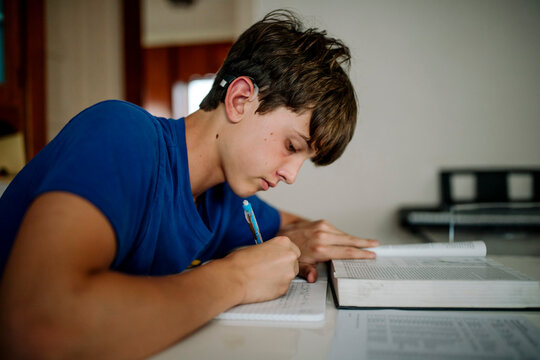 Teen Student with Cochlear Implant Finishing Homework at Home