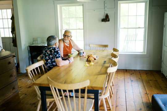 retired gay couple relaxing at home and sitting by dining table
