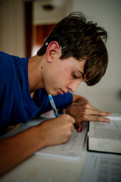 Teen Student with Cochlear Implant Writing Notes While Studying