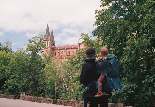 Anonymous man with baby in a backpack carrier looking at the cathedral