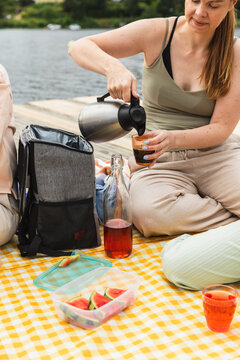 Woman pouring coffee during a lakeside picnic