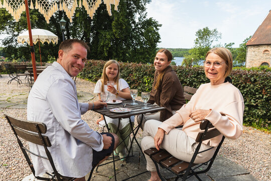 Multigenerational family sitting at cafe table smiling at camera