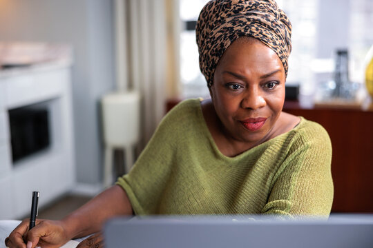 Focused woman working on a laptop and taking notes