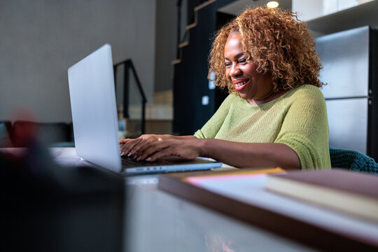A smiling woman working on her laptop at home