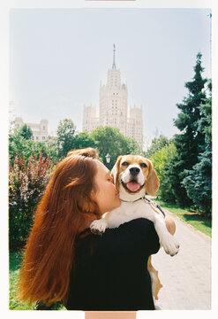 A beagle peers over a shoulder as the city rises behind
