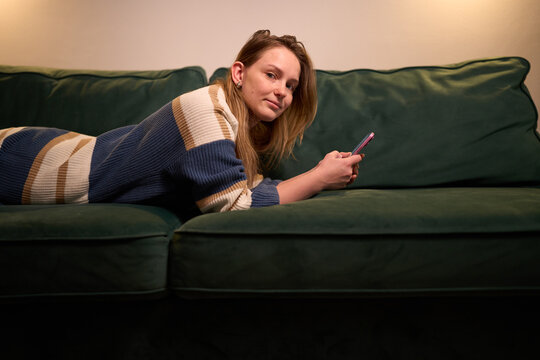 Woman resting on couch with smartphone during quiet evening