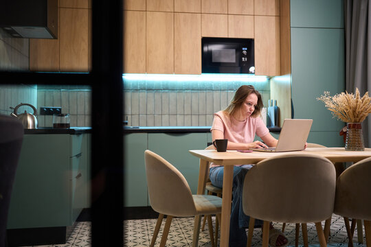 Freelance woman focused on laptop while sitting at dining table