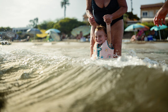 Grandmother helping child playing in ocean waves