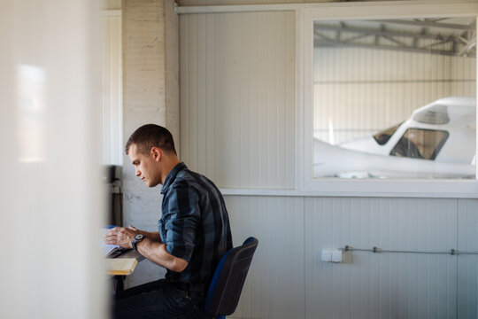 Pilot Studying Flight Plans in Aircraft Hangar Office