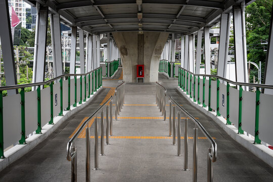 Empty public walkway with metal railing surrounded by city green space