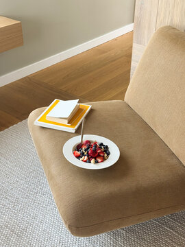 Healthy Berry Oatmeal Bowl on Mustard Yellow Armchair with Books