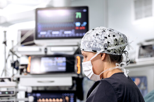 Female medical professional working with anesthesia equipment during surgery in a modern hospital.