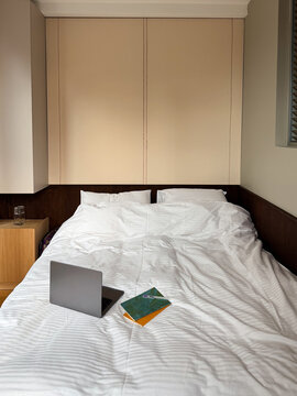 Minimalist Laptop Workstation on Rumpled White Bed in Contemporary Bed
