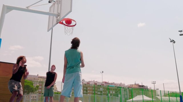 Multicultural friends scoring a goal while playing basketball