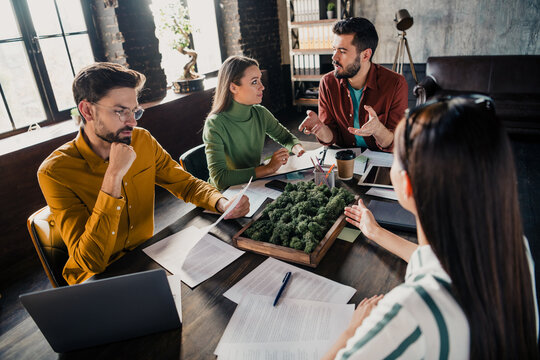 Young creative team discussing sustainable urban landscape model and project plans during a collaborative business meeting in a modern loft office workspace