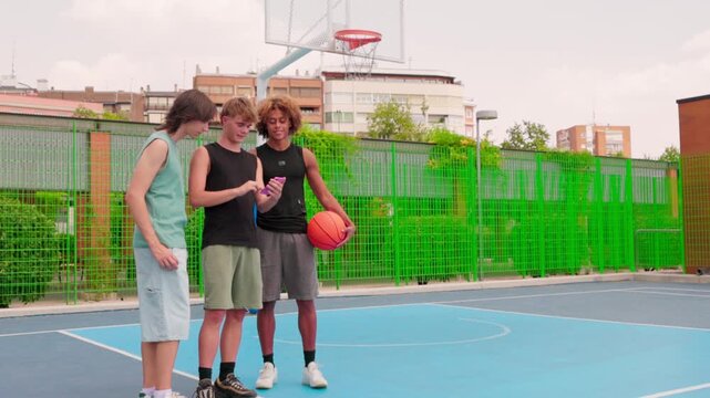 Multicultural friends using a smartphone on a basketball court