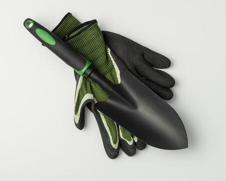 Garden trowel and protective gloves on grey background