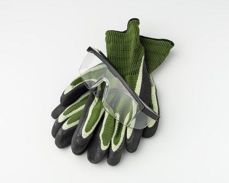 Safety glasses and protective work gloves on grey background