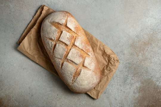 Loaf of artisanal sourdough bread on grey textured background