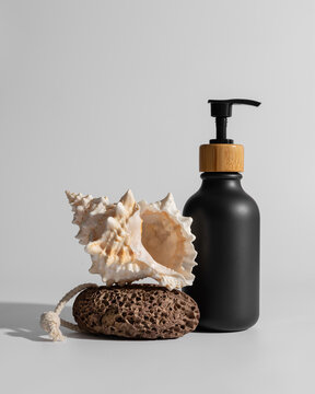 Mock-up featuring a black cosmetic dispenser bottle with pumice stone and seashell