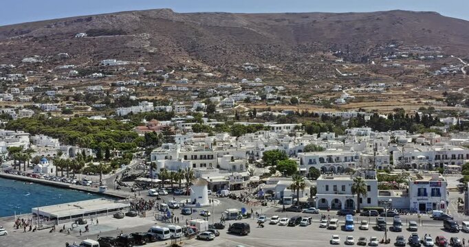 Parikia Paros Greece Aerial v2 low level dramatic flyover harbor area overlooking at the crowded vacation town located along the coast where vessels docked - September 2021