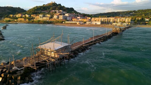 Marina di San Vito Chietino Trabocchi Abruzzo Italy cinematic drone golden sunrise pier two trabocco restaurants beach town view crashing waves ambient sound 4k video