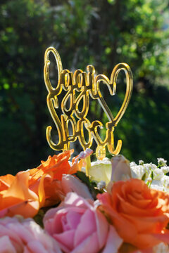 Dettaglio di cake topper in plexiglass dorato con la scritta "Oggi Sposi" e fiori freschi
