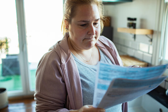 Concerned woman reading a bill in her kitchen