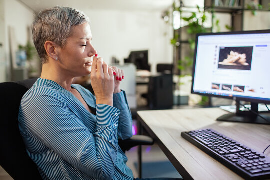 Woman taking a deep breath at office desk