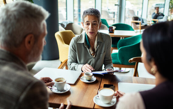 Older woman reviewing documents with a couple in a cafe