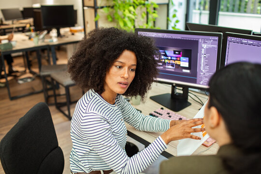 Designer explaining ui mockup to coworker at desk