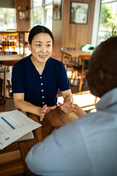 Woman discussing paperwork with colleague in coffee shop