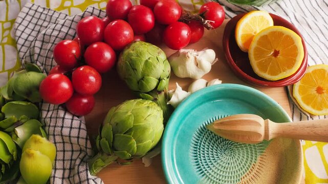 Fresh tomatoes, artichokes, garlic and lemon arranged on a kitchen table before cooking. Natural ingredients for Mediterranean cuisine.