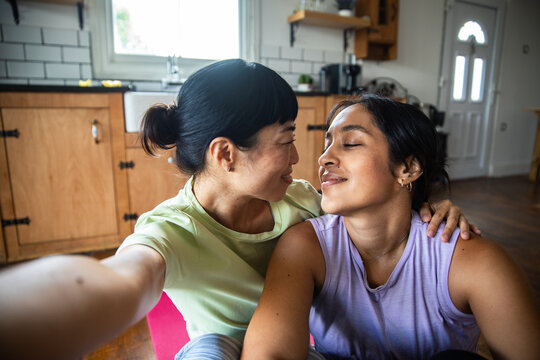 Two women hugging during a post-workout selfie at home