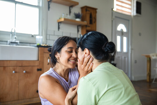 Two women share a tender moment in the kitchen