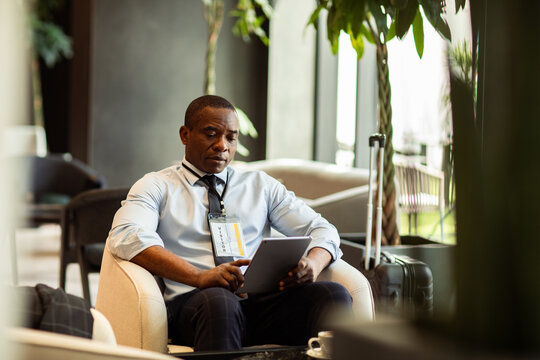 Business visitor using tablet in lobby with luggage