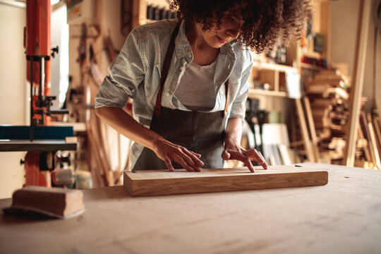 Female carpenter inspecting wooden board in workshop