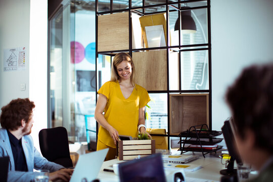 Smiling woman unpacks personal items at modern office desk