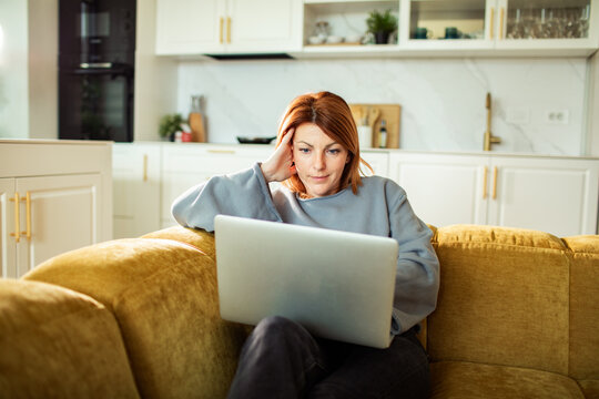 Woman using laptop on sofa at home